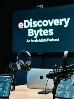 A modern podcast studio featuring a sleek welllit setup with highquality microphones and headphones The background displays a large logo of eDiscovery Bytes  An Avalon Insights Podcast prominently The room is filled with soundproof panels-1-1